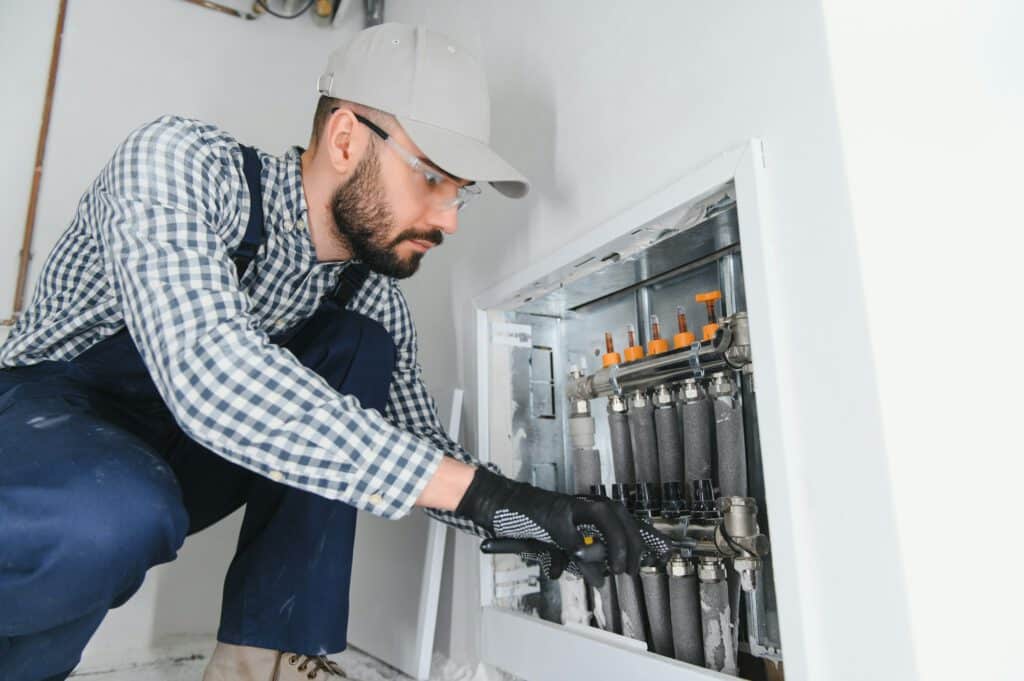 Handwerker arbeitet an einem Heizkreisverteiler